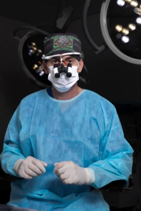 Dr. Gabriel H. Fachini paramentado, com lupa cirúrgica, no centro cirúrgico