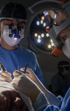 Dr. Gabriel H. Fachini durante procedimento de transplante capilar, com lupa cirúrgica